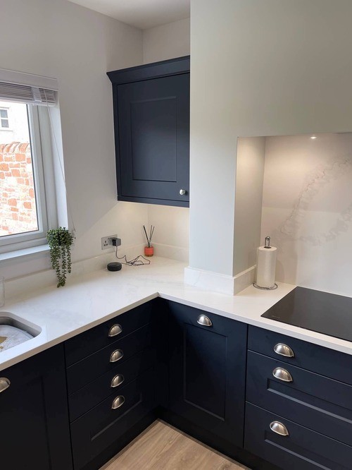 A shaker kitchen with blue cabinets, white walls and worktop