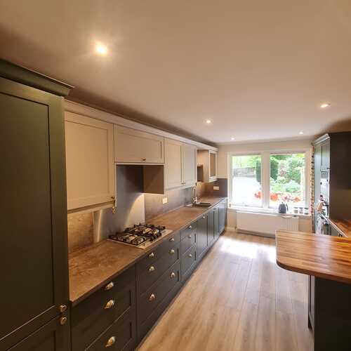Galley kitchen with dark green base units and wooden worktops