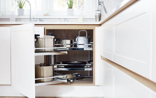 Corner cabinet with pull-out shelves storing pots and kitchen appliances
