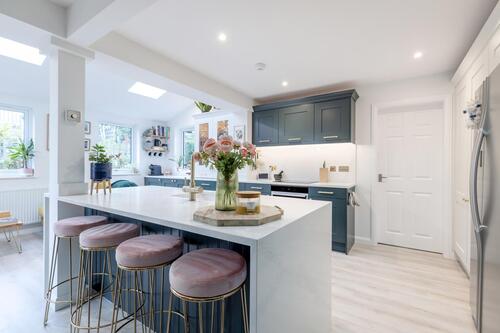 Bright kitchen with white island, navy cabinets, and pink velvet barstools