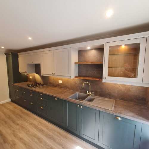 Two-tone kitchen with green base units and brass tap