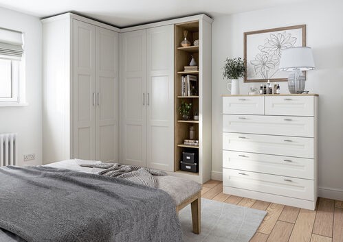 minimalist bedroom with built-in wardrobe, white dresser, and grey bedding
