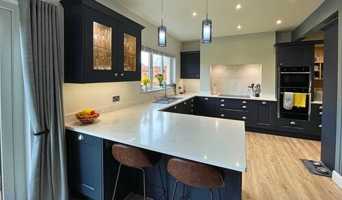 Modern grey kitchen with white countertops and large windows
