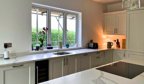 Modern grey kitchen with white countertops and large windows