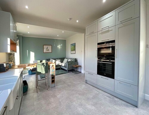 White kitchen cabinets with wooden countertops and grey tile backsplash