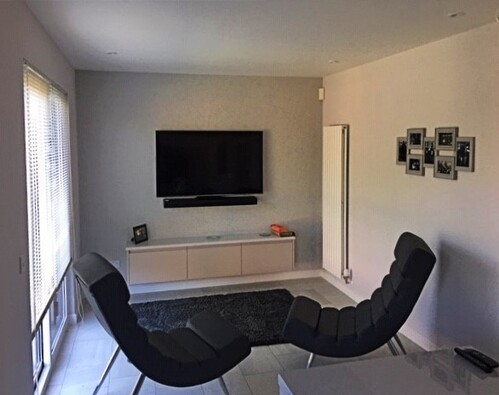 White kitchen cabinets with wooden countertops and grey tile backsplash