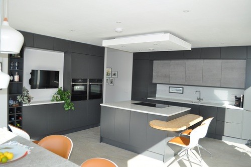 Sleek grey open-plan kitchen with white worktops and bar stools.
