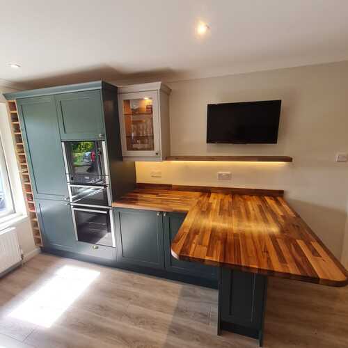 Compact kitchen island with wooden breakfast bar and green cabinets
