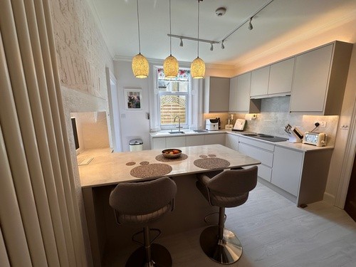 close-up of modern kitchen island with cloud quartz worktop, matt cashmere cabinetry, and integrated sink in contemporary fitted kitchen design