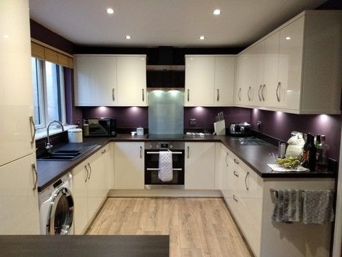 U-shaped white kitchen with purple splashback and black counters