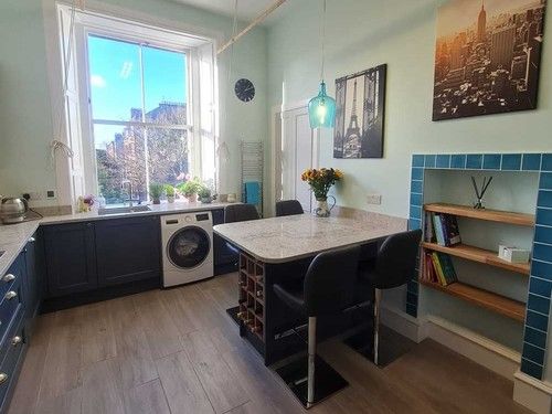 Urban kitchen-diner with navy cabinets, turquoise tiles and city view window