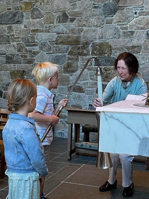 Children learning to prepare the altar candles with a St. Barnabas volunteer