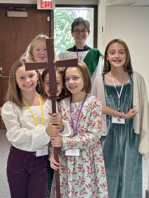 Youth and clergy gathered around a wooden cross