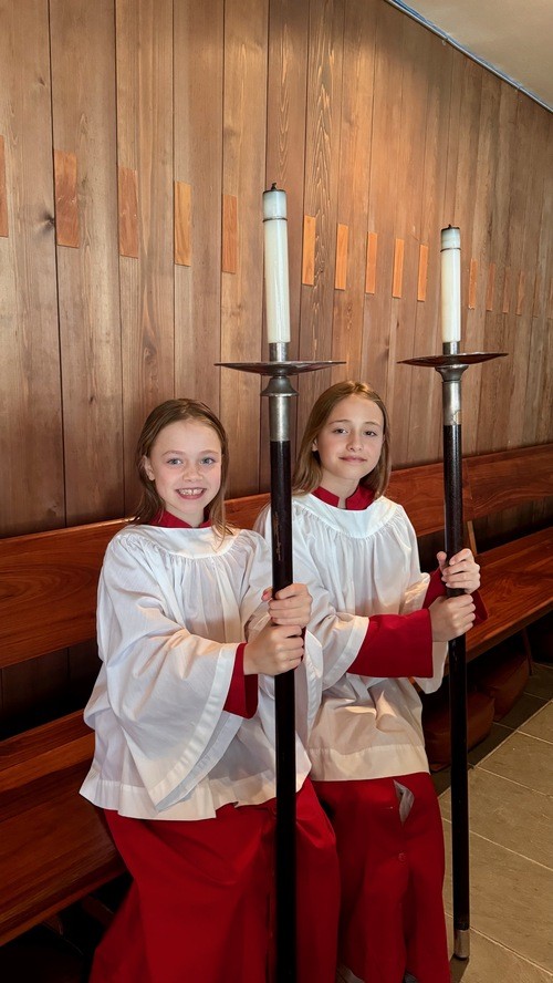 Two young torch-bearers holding candles in church