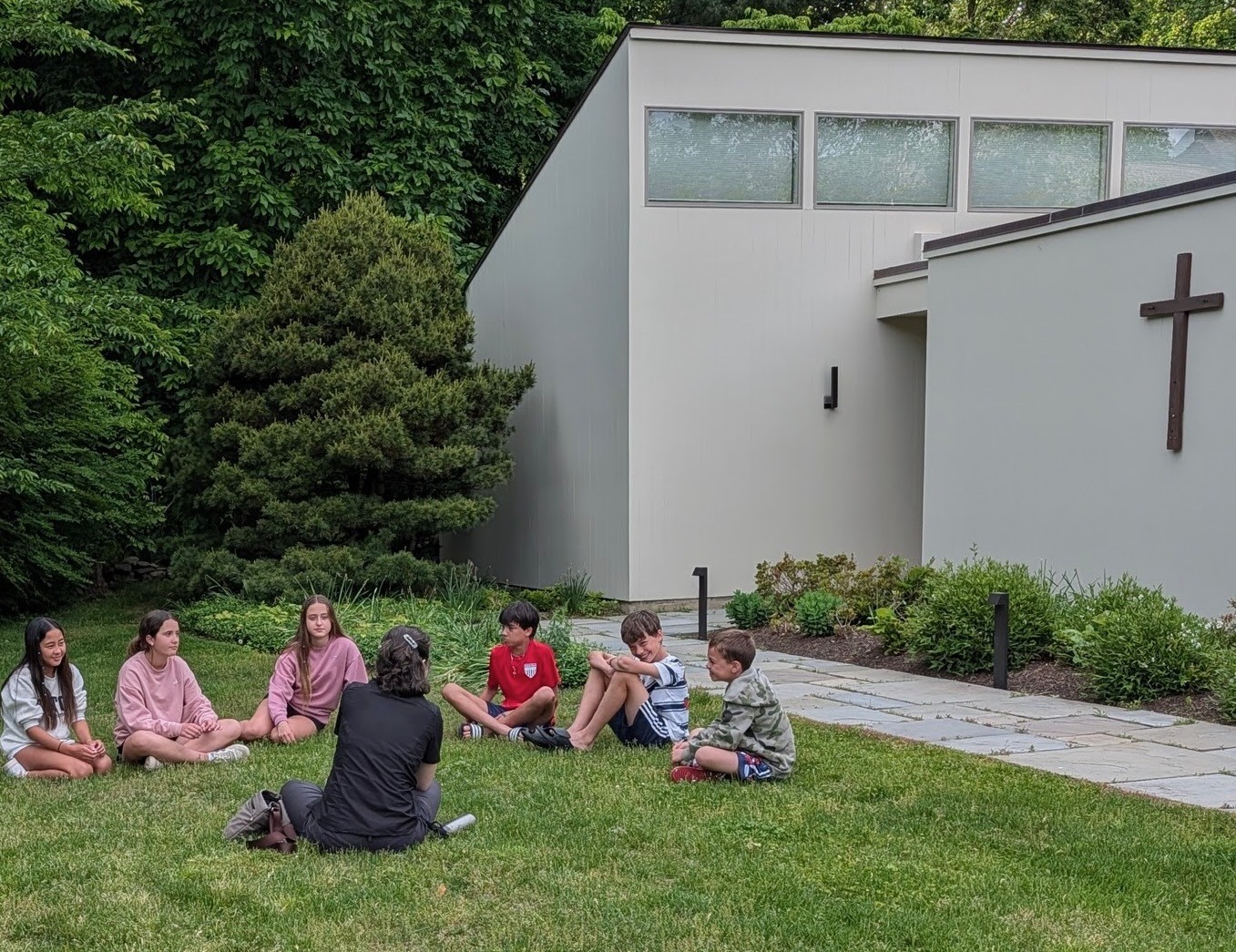 Young people and their leader sharing a conversation on the church lawn