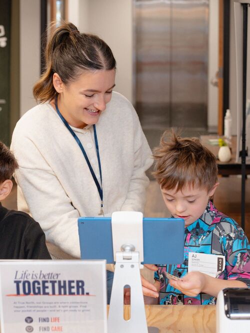 volunteer staff signs in boy to kids church