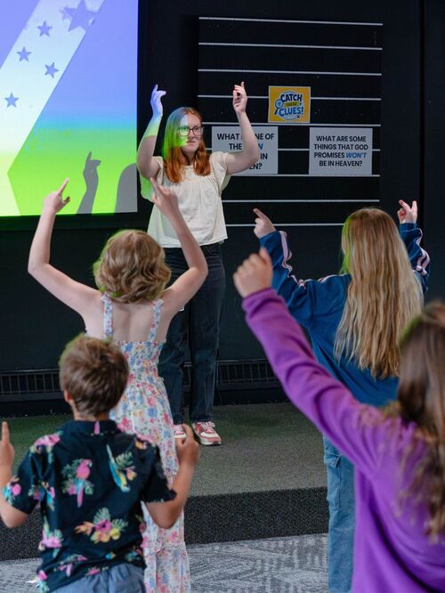 Group of kids singing and lifting their hands in praise
