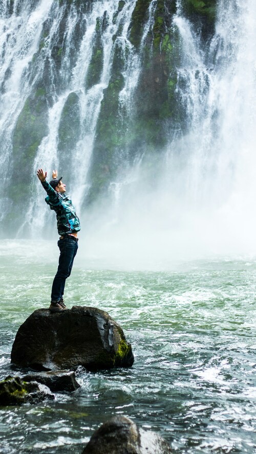 The Clean Life addiction recovery and trauma recovery resources, image of a man standing on rock by waterfall.
