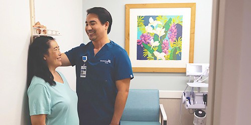 male medical assistant measuring height of female patient