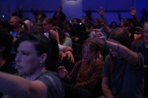 Students with hands raised in prayer at NextGen Conference, Central Triad Church