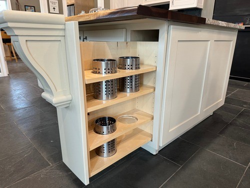 Kitchen island with open shelving, featuring metal storage containers on light wood shelves, and a white paneled exterior.