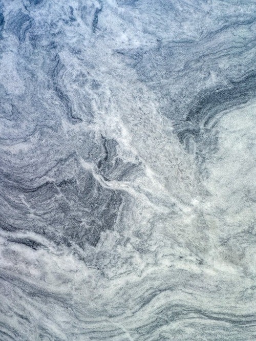 Close-up of a marble surface with a mix of grey and white swirling veining patterns.