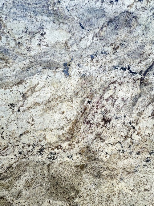 Close-up of a granite surface with a mix of beige, brown, and black speckles and veining.