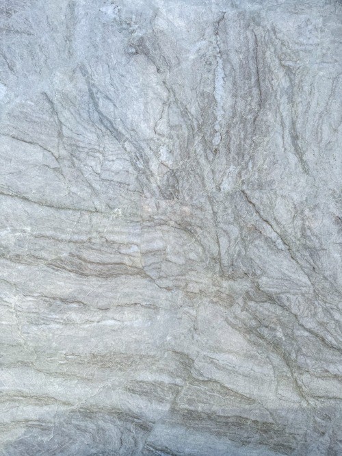 Close-up of a quartzite surface with a grey background and subtle, flowing veining patterns.