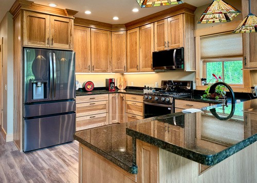  Modern kitchen with wooden cabinets, black granite countertops, stainless steel appliances, and pendant lights.