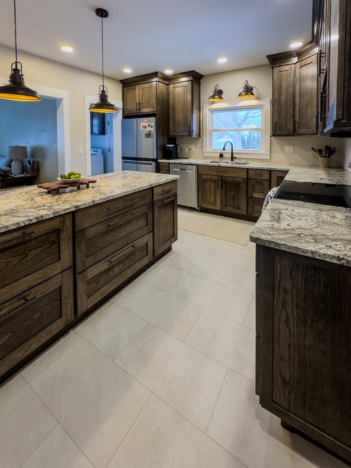 Modern kitchen with gray cabinets, marble countertops, stainless steel appliances, and pendant lights.