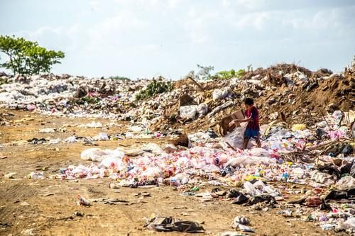 Boy At Trash Pile In India.