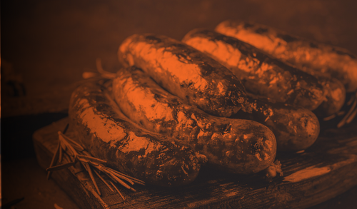 Grilled sausages on a cutting board representing the Sausage and Sizzle church fellowship event at UHBC in Stillwater, Oklahoma