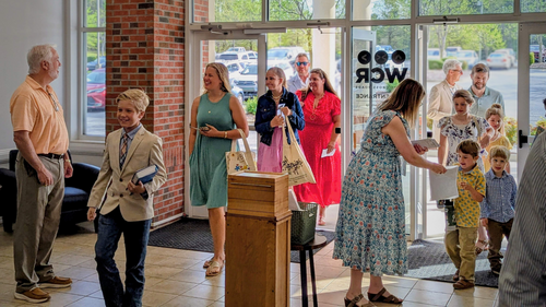 Wake Cross Roads Baptist Church welcomes you! Photo shows happy people welcoming each other in the church lobby.
