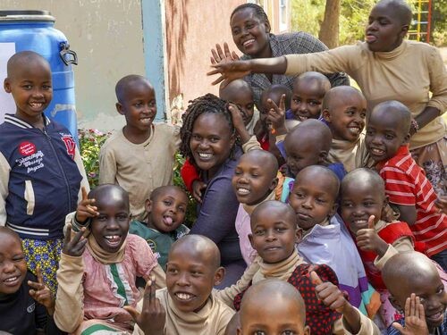 Smiling Kenyan children and their caretaker at Kathonzweni Children's Home.