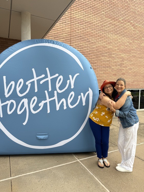 Two women beside the Life Is Better Together display