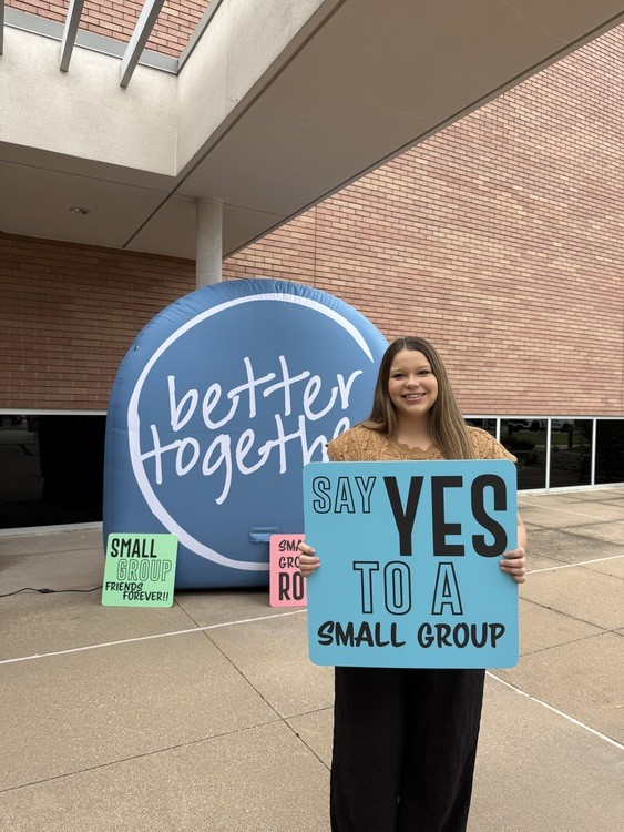 A woman holding a Say Yes to a Small Group sign