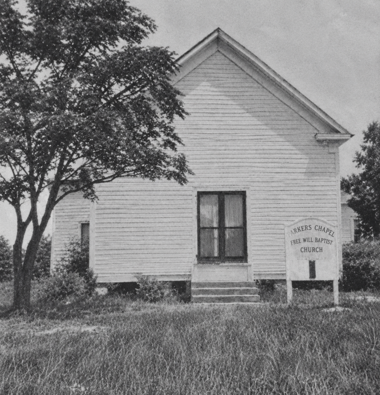 Historic black-and-white photograph of the wooden Parkers Chapel church and its Free Will Baptist Church sign.