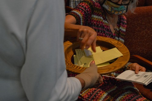 An usher hold the offering plate for a woman during Sunday morning service