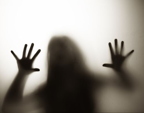 Diffused silhouette of woman through frosted glass