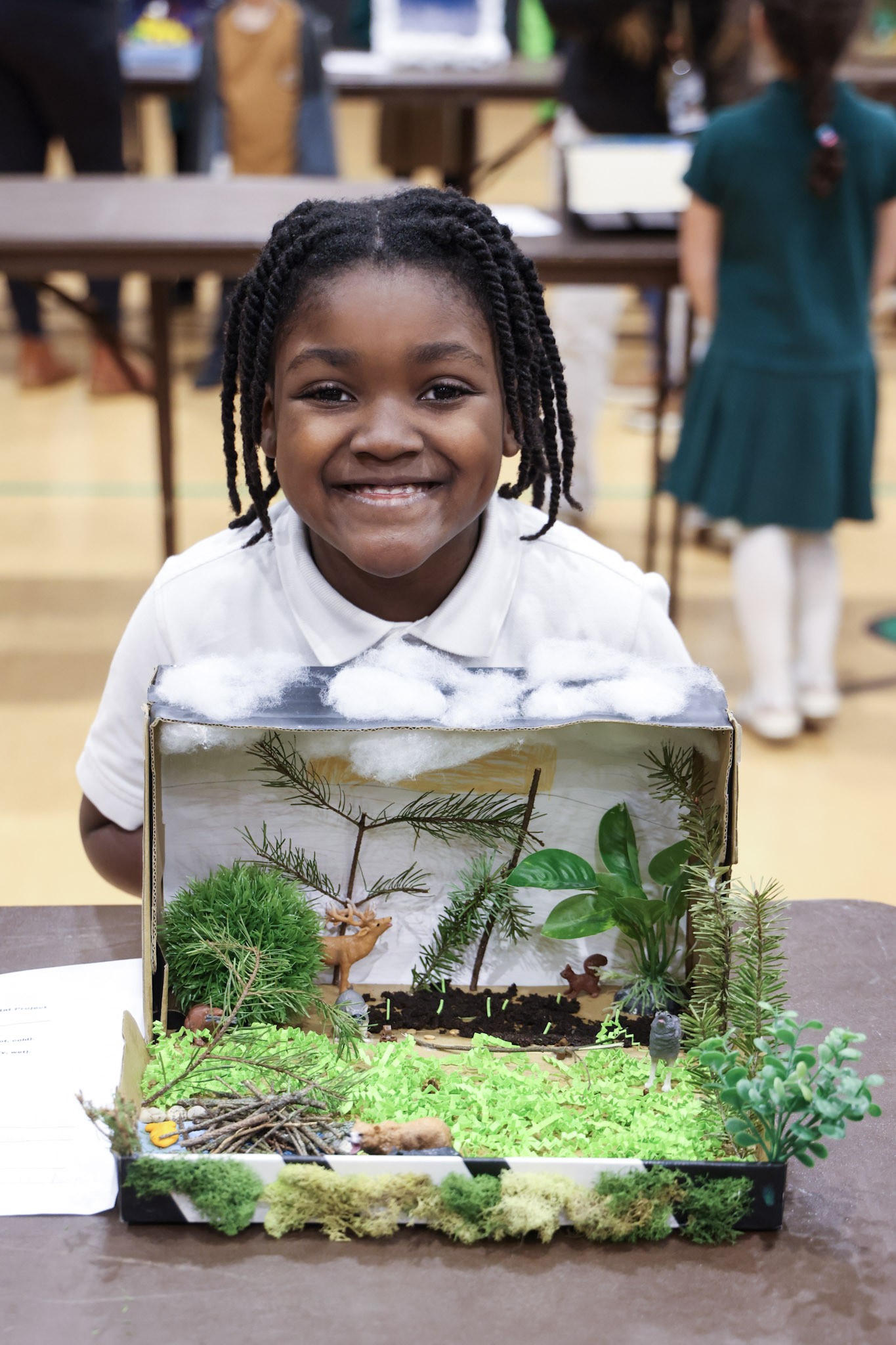 Second-grade student proudly displaying a habitat model
