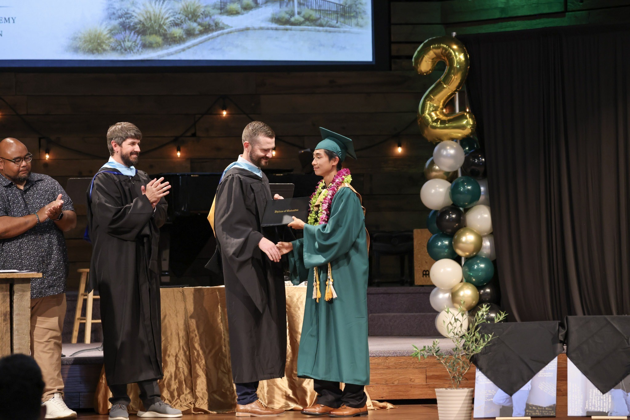 HCA graduate receiving diploma with faculty at graduation