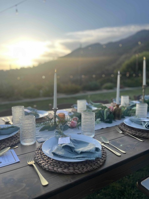 Taper candles and glassware glowing across the sunset table
