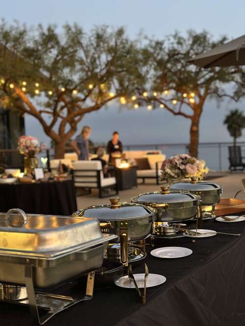 The sunset buffet beneath string-lit trees with the coast beyond