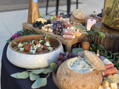 A generous grazing table with fruit, cheese, bread, and caprese salad