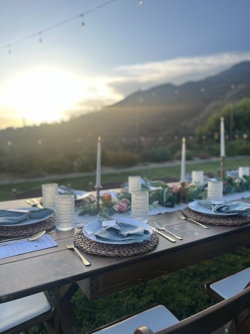 Sunlit table settings with taper candles overlooking the hillside
