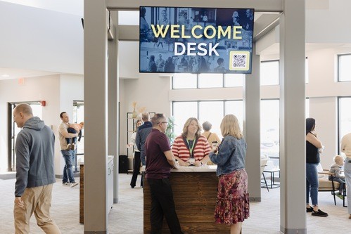 Laura standing at the Welcome Desk in our main lobby answsering questions of church guests.
