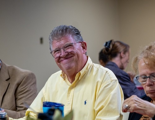 man with beard waving and smiling