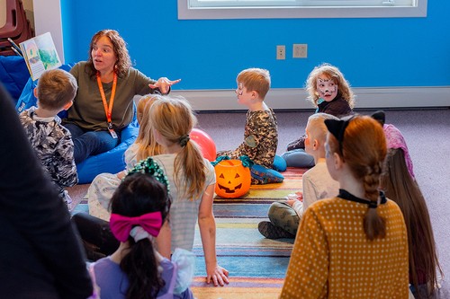 A group of children sitting on the floor and listening to a volunteer read them a story at the Fall Festival at Creekside Church.