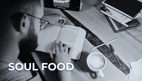 black and white photo of man studying the bible