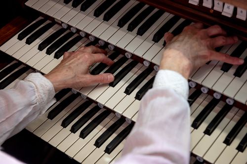 An image of Dr. Parker's hands playing the organ, showing the sleeves of her white shirt.